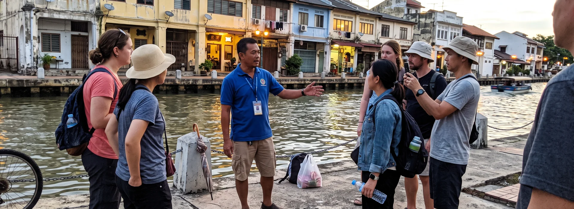 A guide standing with a small group beside the Malacca River