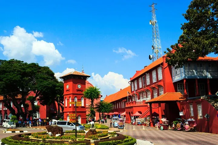 Dutch Square in daylight, the red clock tower and Stadthuys with trishaws parked on the far side