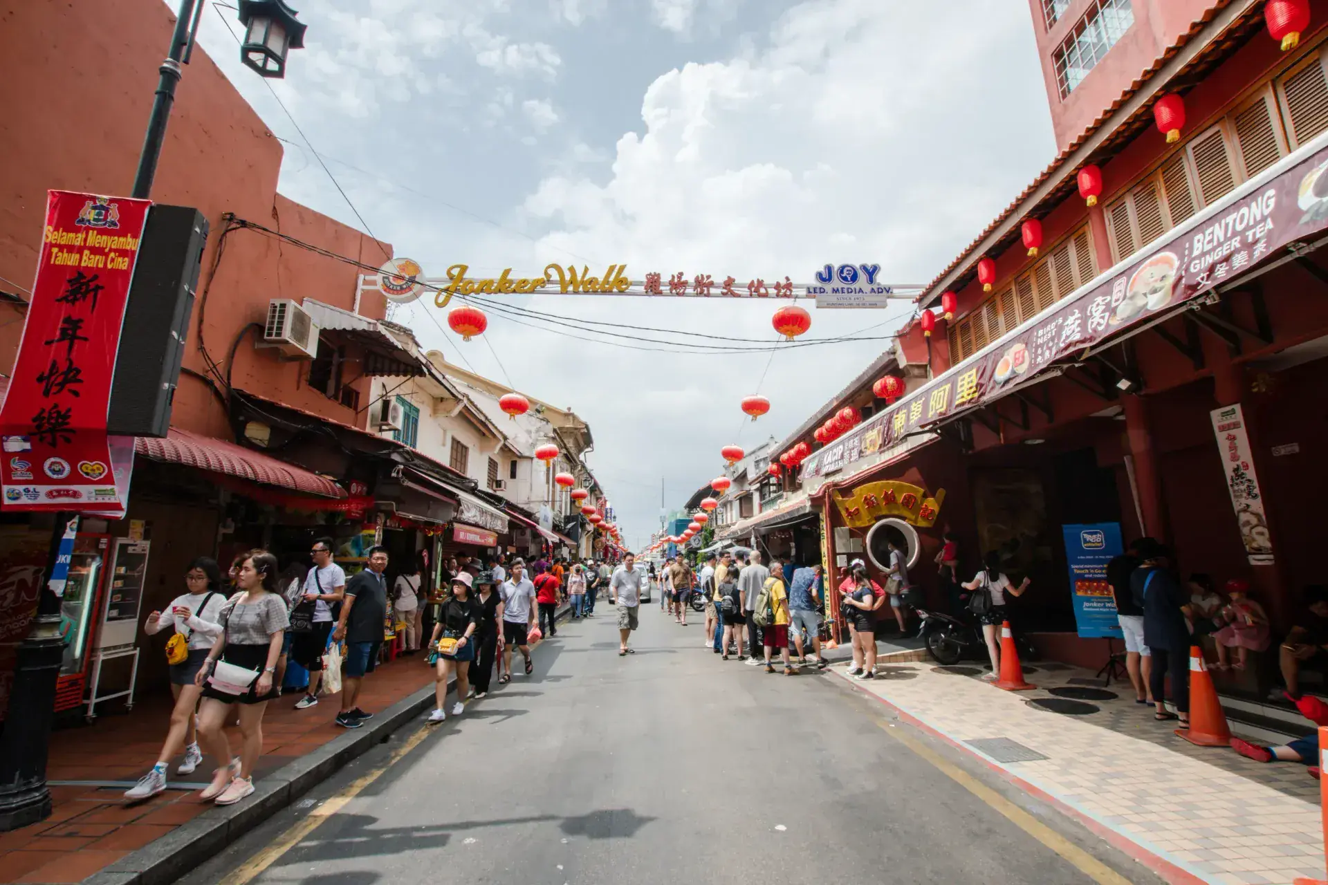 The Jonker Walk archway over Jonker Street in daylight, red lanterns strung above a busy crowd