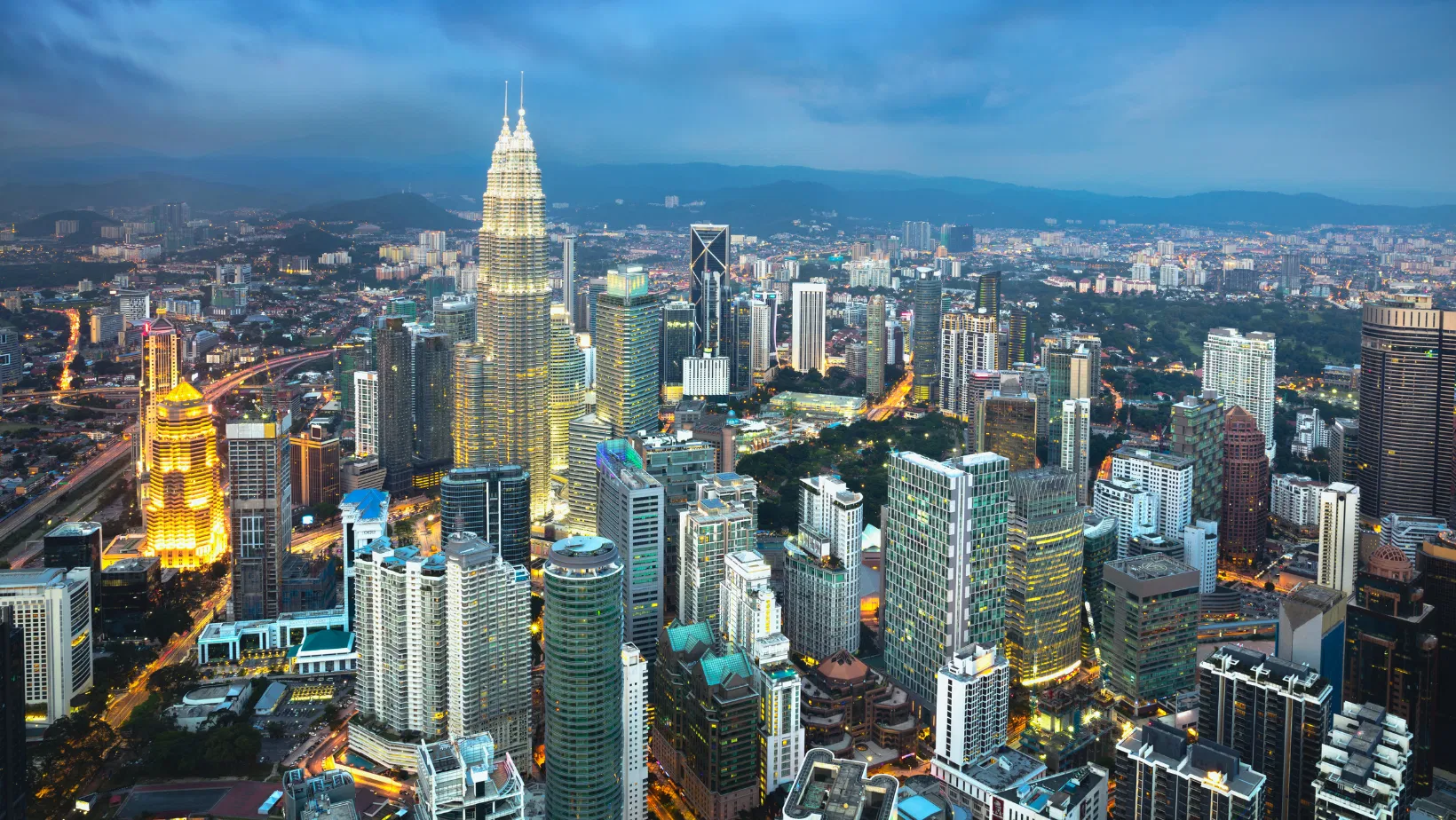The Kuala Lumpur skyline at dusk with the Petronas Twin Towers lit
